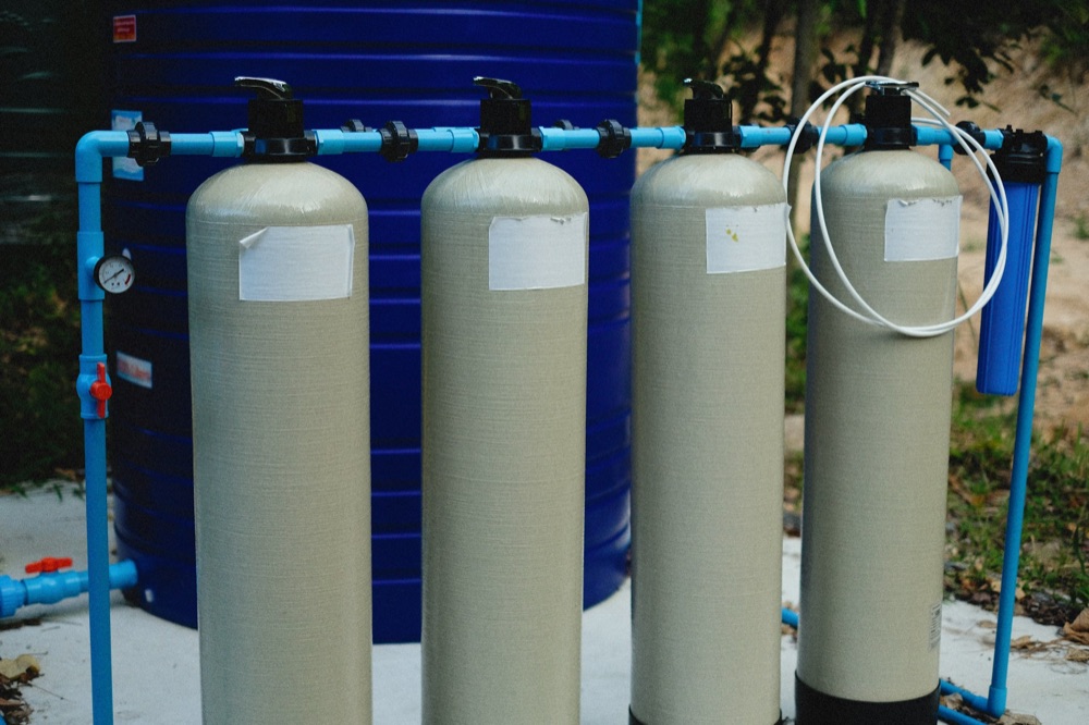 Water treatment and softener system installed beside a home water tank